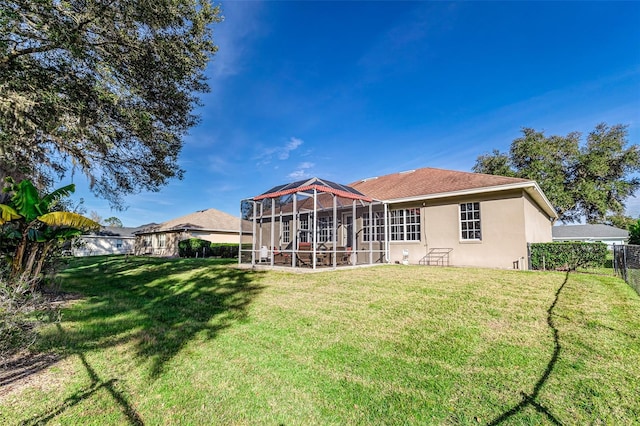 rear view of house featuring a lawn and glass enclosure