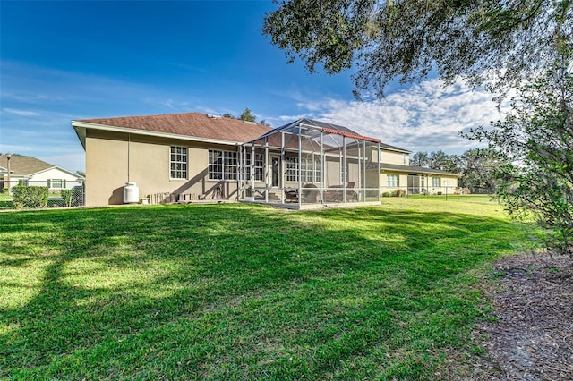 rear view of house featuring a lawn and glass enclosure