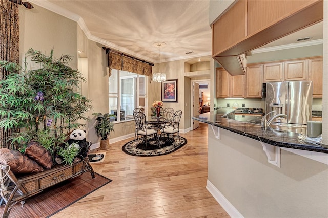 kitchen featuring light brown cabinetry, stainless steel fridge with ice dispenser, ornamental molding, pendant lighting, and light hardwood / wood-style floors