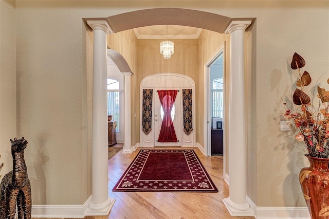 foyer with hardwood / wood-style floors, crown molding, and ornate columns