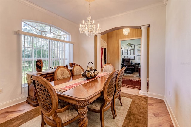 dining area with light hardwood / wood-style flooring, ornamental molding, decorative columns, and a chandelier