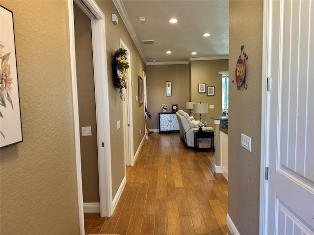 hallway featuring crown molding and light hardwood / wood-style flooring