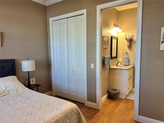 bedroom with crown molding, connected bathroom, light hardwood / wood-style floors, and a closet