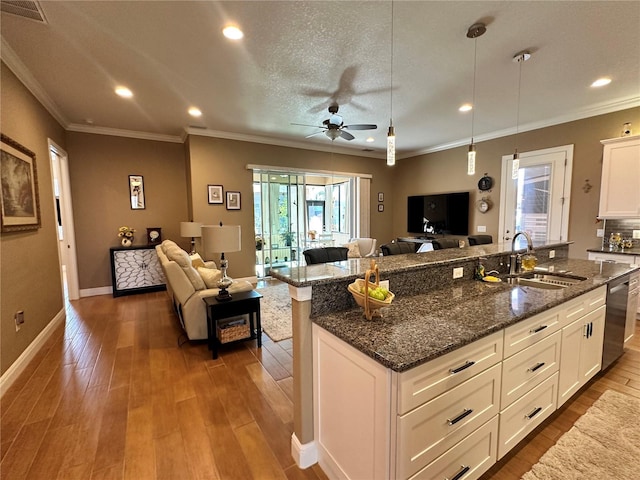 kitchen featuring white cabinetry, pendant lighting, stainless steel dishwasher, and dark stone counters