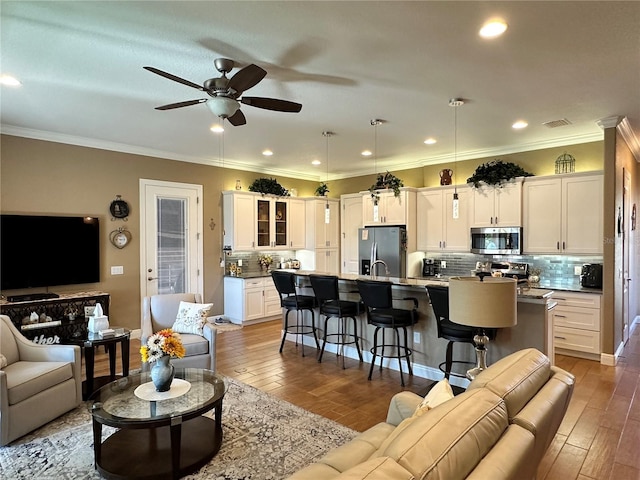 living room with crown molding, hardwood / wood-style floors, and ceiling fan