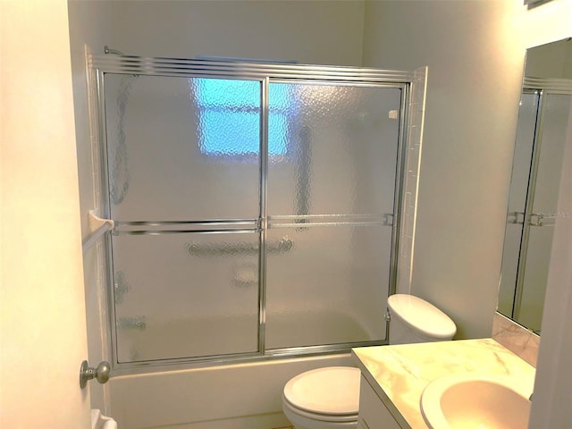 full bathroom with enclosed tub / shower combo, vanity, and toilet