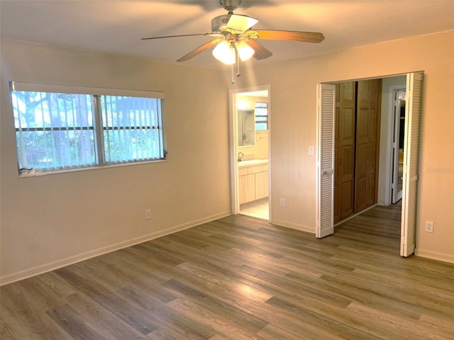 unfurnished bedroom with dark wood-type flooring, ceiling fan, ensuite bathroom, and a closet