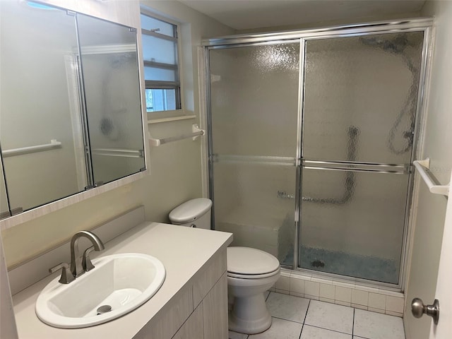 bathroom with tile patterned flooring, vanity, a shower with shower door, and toilet