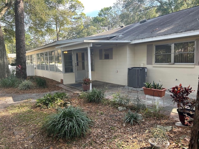 view of front facade with central AC unit, a patio area, and a sunroom