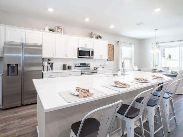 kitchen with sink, stainless steel appliances, white cabinets, and a center island with sink