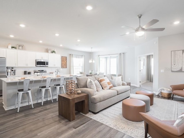 living room featuring dark wood-type flooring and ceiling fan