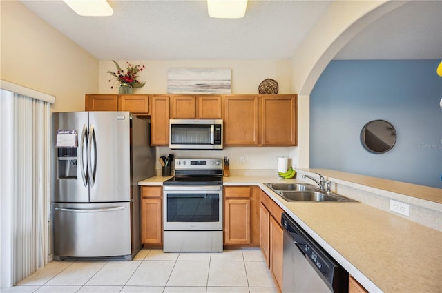 kitchen featuring sink, light tile patterned flooring, a textured ceiling, and appliances with stainless steel finishes