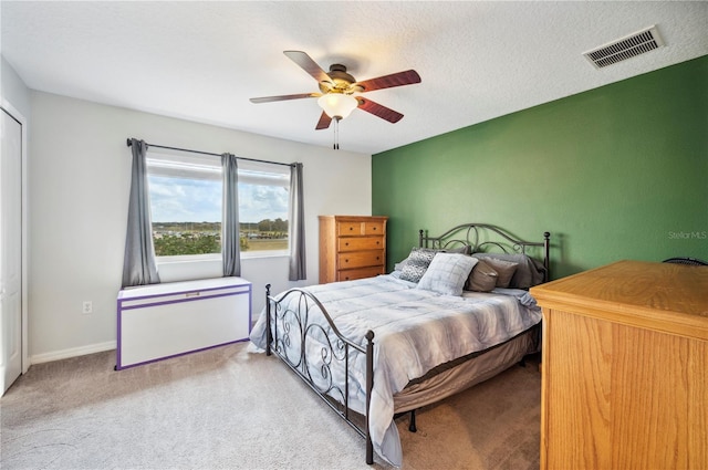 bedroom with a textured ceiling, light colored carpet, and ceiling fan