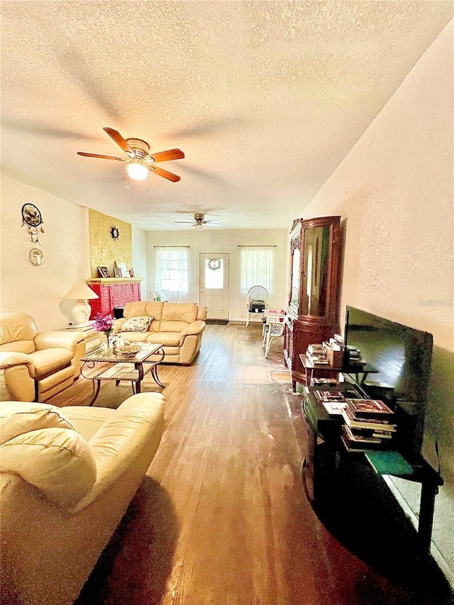 living room featuring ceiling fan, wood-type flooring, and a textured ceiling