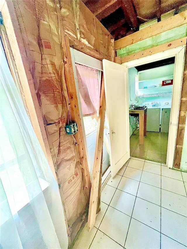 hall with washing machine and clothes dryer and light tile patterned floors