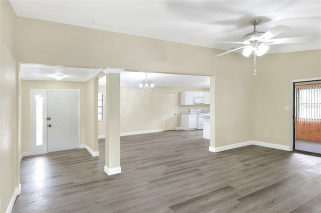 foyer entrance featuring dark wood-type flooring, ceiling fan with notable chandelier, and ornate columns