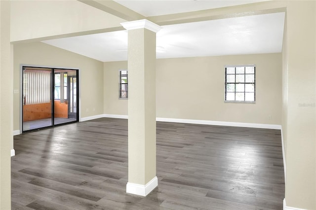 spare room featuring dark hardwood / wood-style floors, lofted ceiling with beams, and ornate columns