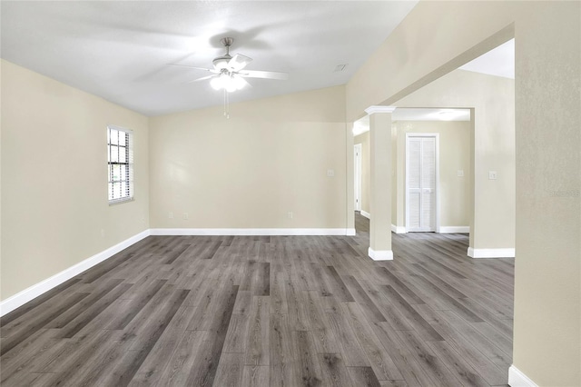 empty room with ornate columns, dark wood-type flooring, and ceiling fan