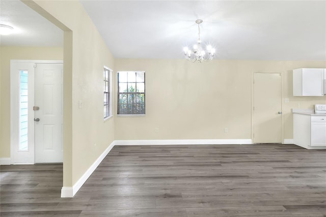 unfurnished dining area with dark hardwood / wood-style floors and a chandelier