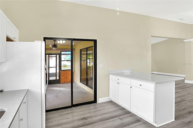 kitchen with white cabinetry, light wood-type flooring, kitchen peninsula, and white fridge