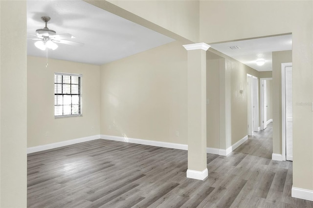 unfurnished room featuring ornate columns, ceiling fan, and light hardwood / wood-style flooring