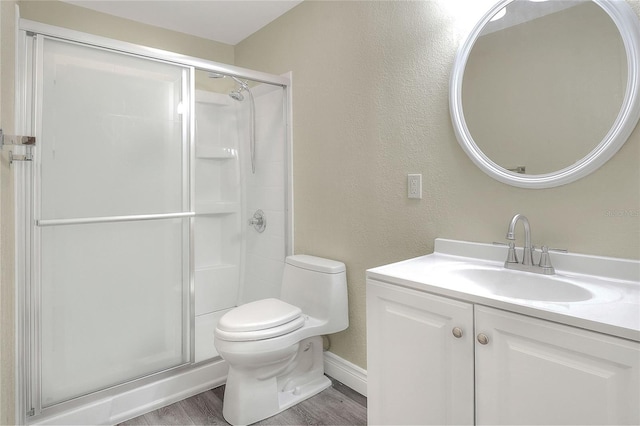 bathroom featuring walk in shower, wood-type flooring, vanity, and toilet