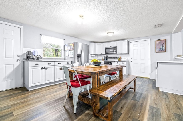 interior space featuring white cabinetry, wood-type flooring, stainless steel appliances, and a textured ceiling