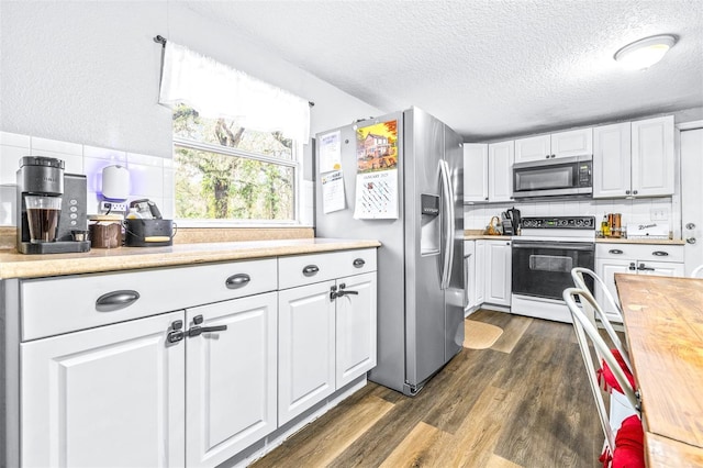 kitchen featuring wooden counters, appliances with stainless steel finishes, tasteful backsplash, a textured ceiling, and white cabinets