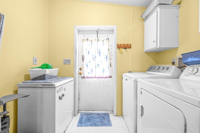 laundry area featuring cabinets, washer and dryer, and a textured ceiling