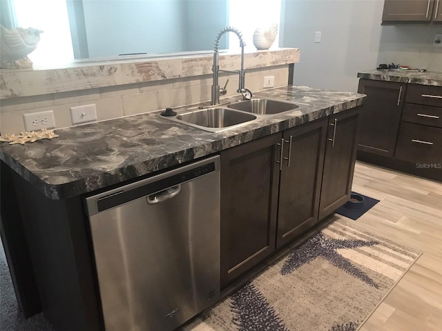 kitchen featuring sink, dishwasher, a kitchen island with sink, and light wood-type flooring