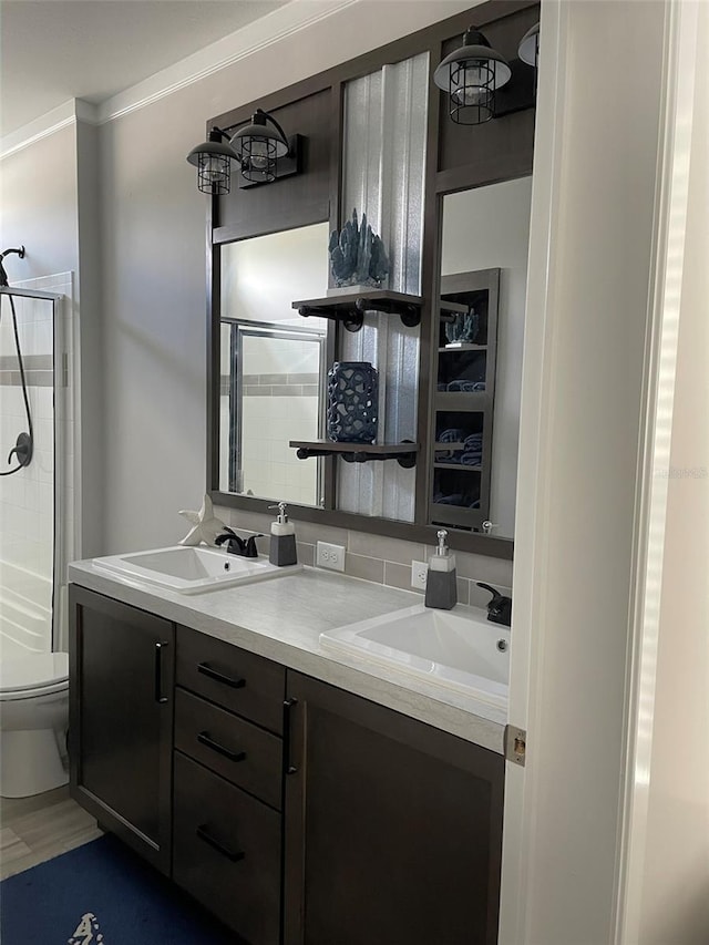 bathroom featuring crown molding, vanity, toilet, and a shower with shower door