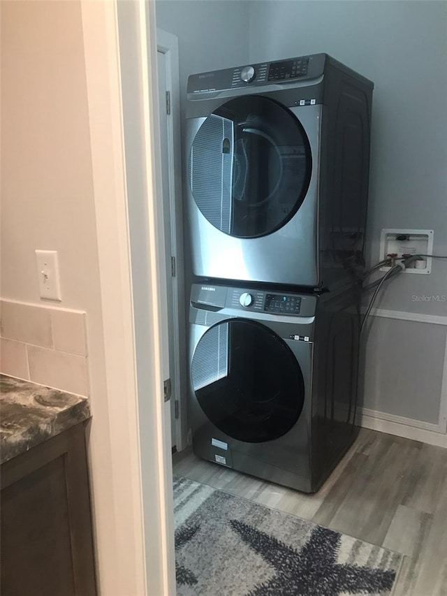 laundry area featuring stacked washer / drying machine and light hardwood / wood-style floors