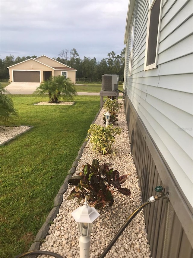 view of yard with a garage and central AC