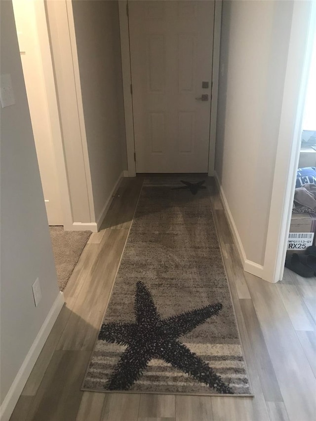hallway featuring wood finished floors and baseboards