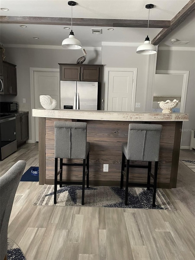 kitchen with light wood-style floors, visible vents, beamed ceiling, a breakfast bar area, and stainless steel appliances