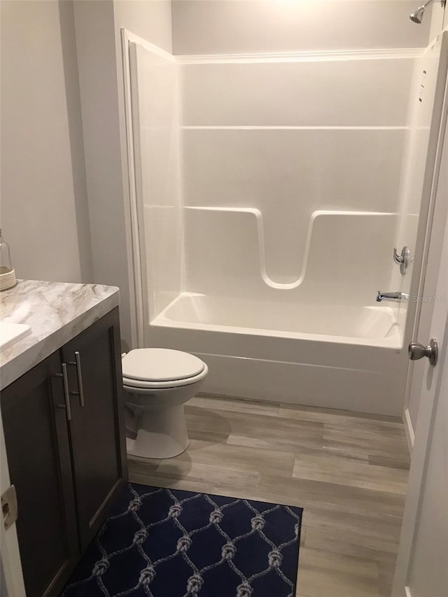 bathroom with toilet, vanity, wood finished floors, and shower / bathtub combination