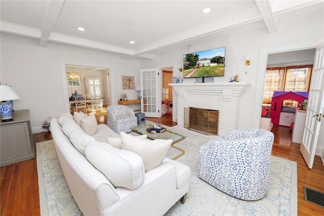 living room featuring french doors, beamed ceiling, and light wood-type flooring