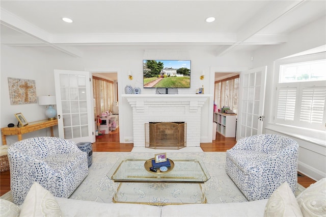 living room featuring hardwood / wood-style flooring, a fireplace, coffered ceiling, and beam ceiling