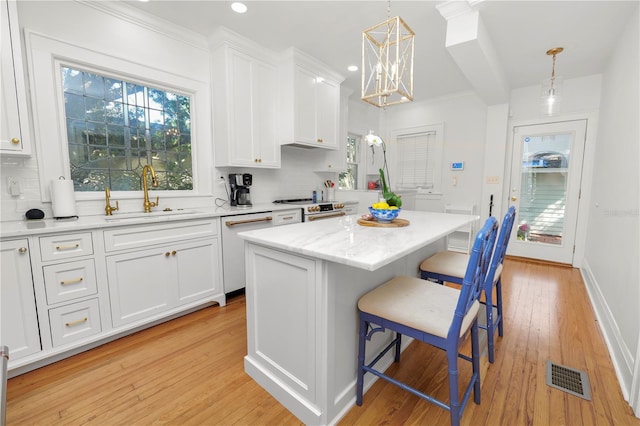 kitchen with a kitchen island, white cabinetry, sink, a kitchen bar, and white dishwasher