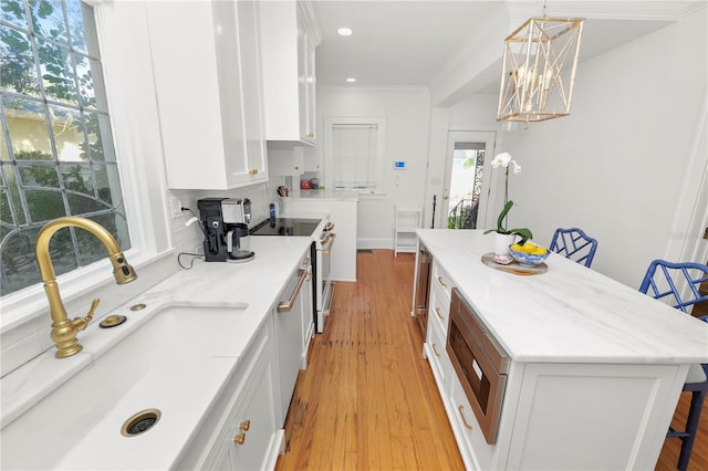 kitchen featuring a kitchen bar, sink, decorative light fixtures, a center island, and white cabinets