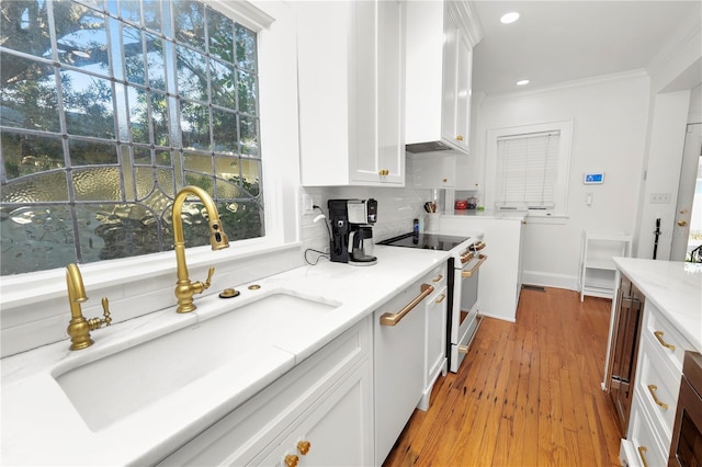 kitchen featuring tasteful backsplash, white cabinetry, high end white range, sink, and ornamental molding