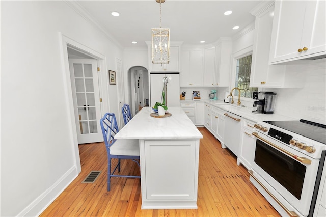 kitchen with sink, white appliances, white cabinetry, a kitchen breakfast bar, and a kitchen island