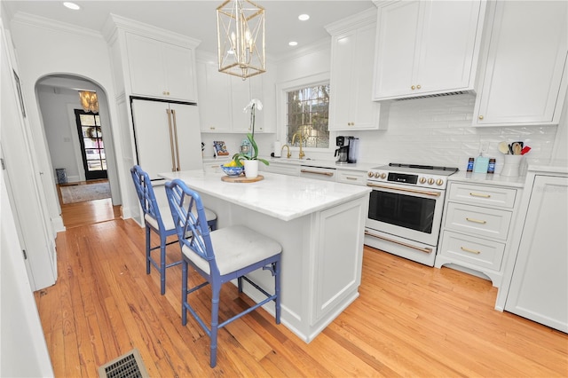 kitchen with white cabinetry, a center island, white appliances, and a breakfast bar