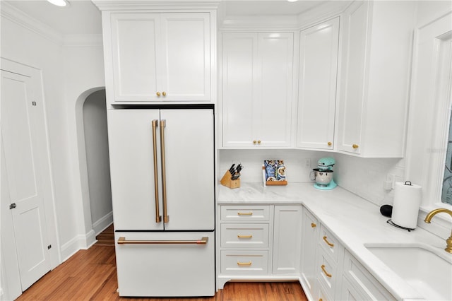 kitchen with white cabinetry, high end fridge, sink, and light hardwood / wood-style floors