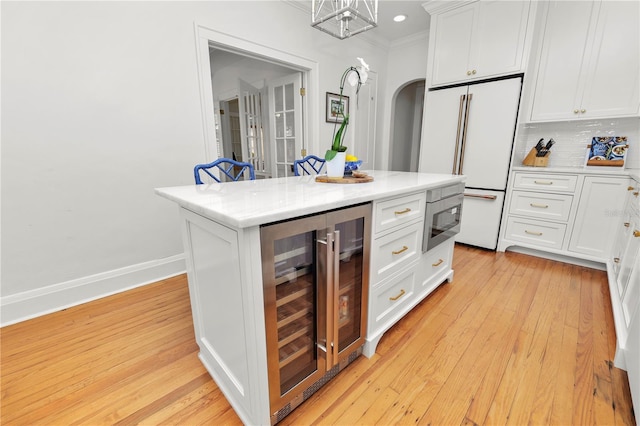 kitchen with high end white refrigerator, a center island, wine cooler, and white cabinets