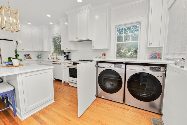 laundry room featuring ornamental molding, plenty of natural light, light hardwood / wood-style floors, and washer and dryer