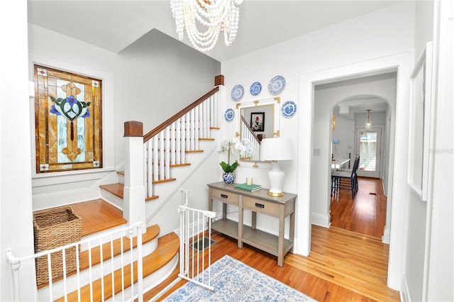 stairs featuring wood-type flooring and a chandelier