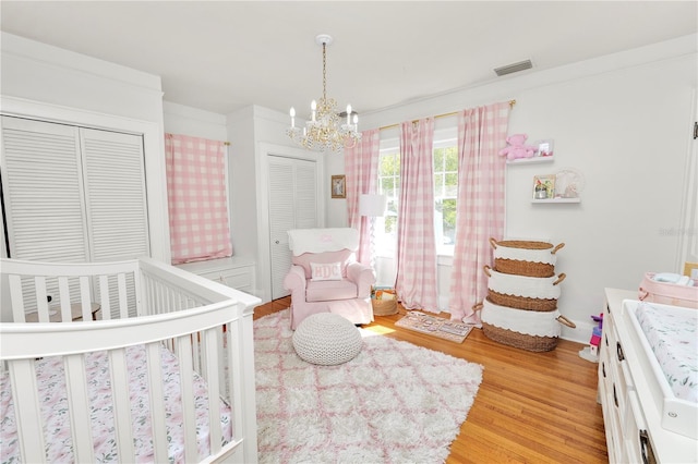 bedroom with a notable chandelier, a crib, and light wood-type flooring