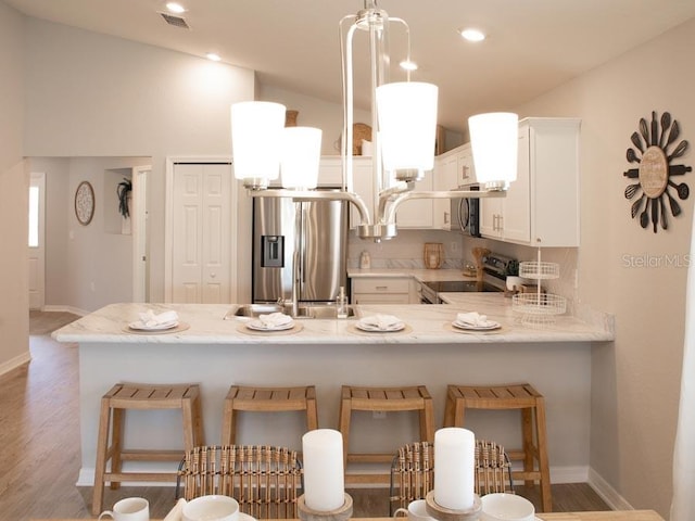 kitchen featuring appliances with stainless steel finishes, a breakfast bar, white cabinetry, sink, and kitchen peninsula