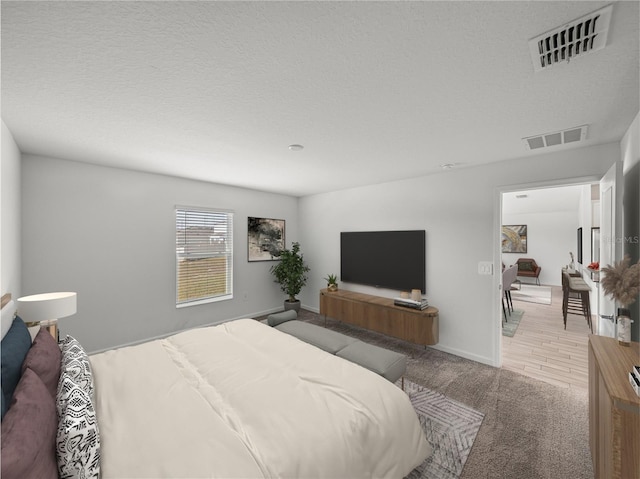 bedroom featuring light colored carpet and a textured ceiling